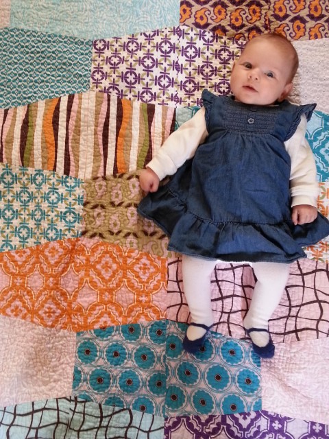 baby laying on a color quilt